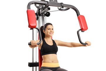 Wall Mural - Young female exercising on a multifunctional fitness machine