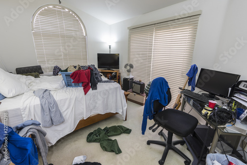 cluttered, messy teenage boys bedroom with piles of clothes