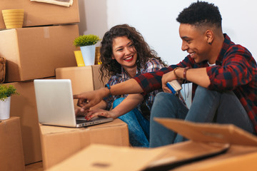 Happy young couple moving into their new home. They sitting on the floor and choosing colors for the walls.