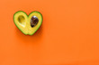Heart-shaped avocado on orange background