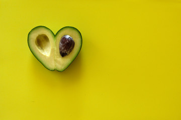 Poster - Heart-shaped avocado on yellow background