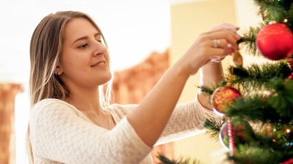 Portrait of beautiful young woman preparing Christmas tree for winter holidays