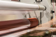Big printing laminator armed with glossy paper rolls and transparent film.