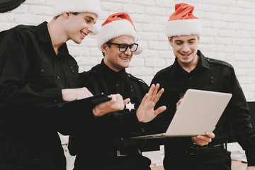 Wall Mural - Officers In A Santa Claus Caps Staring On Laptop.