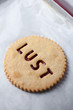 Biscuit with LUST written in jam