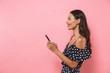 © Drobot Dean - Side view of Happy brunette woman in dress holding smartphone