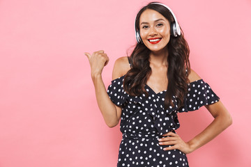 Canvas Print - Smiling brunette woman in dress and headphones listening music