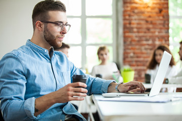 Portrait of young man sitting at his desk in the office