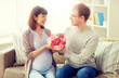 © Syda Productions - pregnancy, holidays and people concept - happy husband giving flowers to his pregnant wife for birthday at home