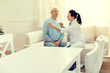 © Viacheslav Yakobchuk - Preventive visit. Cheerful elderly man sitting on a sofa while a female doctor listening to his heart beating and lungs.