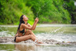 Beautiful women in sexy bikini happy playing a water along the riverside. Young women enjoy playing water alone outdoor.