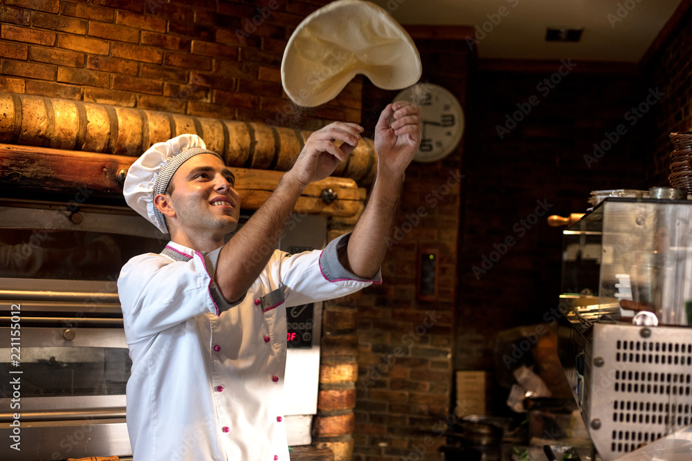 Skilled chef preparing dough for pizza rolling with hands and throwing up - obrazy, fototapety, plakaty 