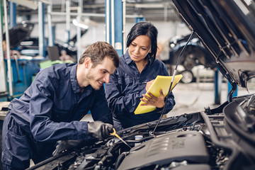 Wall Mural - Auto car repair service center. Two mechanics - man and woman examining car engine