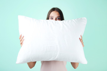 Young girl with white pillow on mint background