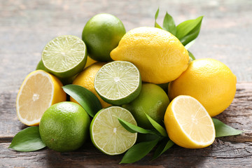 Canvas Print - Lemons and limes with green leafs on grey wooden table