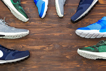 Top View Shop Display Of Unbranded Modern New Stylish Sneakers Running Shoes For Men On Wooden Background Texture With Copy Space.