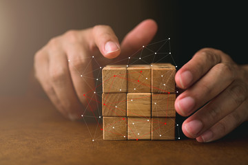 business man try to build wood block on wooden table and blur background business organization startup concept