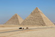 Zwei Pyramiden, darunter Cheops, in Ägypten bei Kairo mit einer Straße und ein Auto und Kamele davor.