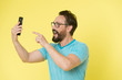 © be free - Guy eyeglasses cheerful pointing at smartphone. Man happy user interact application for smartphone. Guy bearded interact mobile interface application. Man excited about new opportunities