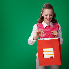 Wall Mural - smiling young student woman looking at shopping bag with books