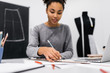 © Oleksii - African American university student drawing, sketching, painting at workplace focus on hand. Beautiful curly hair woman working project in atelier.