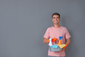 Poster - Man with cleaning supplies on color background