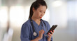 © Mark Adams - Serious millennial doctor on break reading texts with smartphone inside hospital