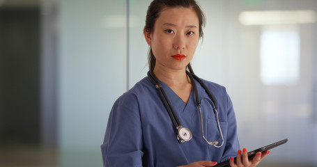 Wall Mural - Chinese millennial nurse or medical doctor using tablet computer in hospital