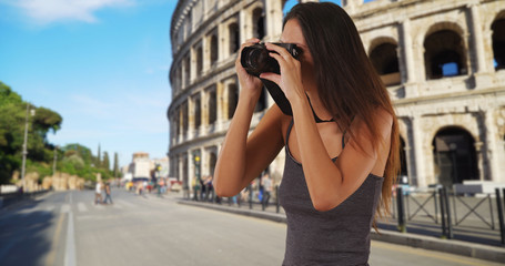 Wall Mural - Young tourist woman standing near the Roman Coliseum taking picture with camera