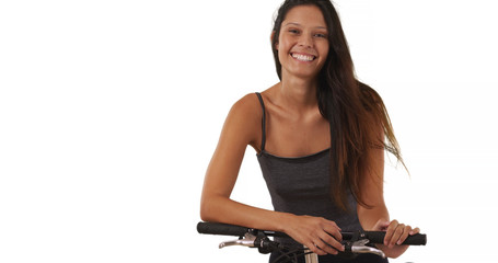 Wall Mural - Pretty brunette female with her bike on white background smiling at camera