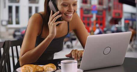 Wall Mural - Female tourist in outdoor cafe with laptop chatting on cellphone