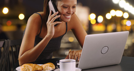 Wall Mural - Young woman talking on mobile phone and working on laptop outside at night