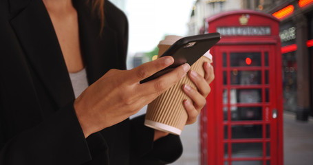 Close up of female hands text messaging on smartphone while downtown in London