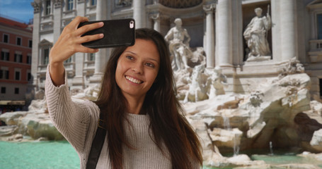 Wall Mural - Millennial woman in italy taking phone selfie in front of Trevi Fountain