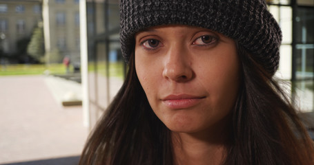 Wall Mural - Close up portrait millennial woman wearing beanie making eye contact with camera