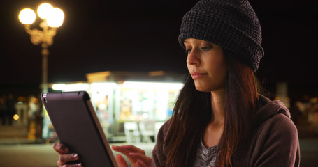 Wall Mural - Millennial caucasian girl using tablet computer on city street at night