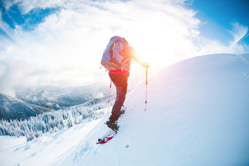 A man in snowshoes in the mountains in the winter.