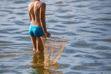 a boy is catching a fish net in the pond