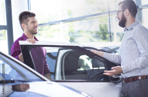 Fotografie, Obraz Putative buyer talking to a car dealer next to a car