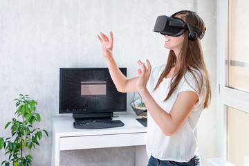 Wall Mural - Smiling positive woman wearing virtual reality goggles headset, vr box. Connection, technology, new generation, progress concept. Girl trying to touch objects in virtual reality