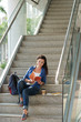 © DragonImages - Female university student sitting on steps and reading a book