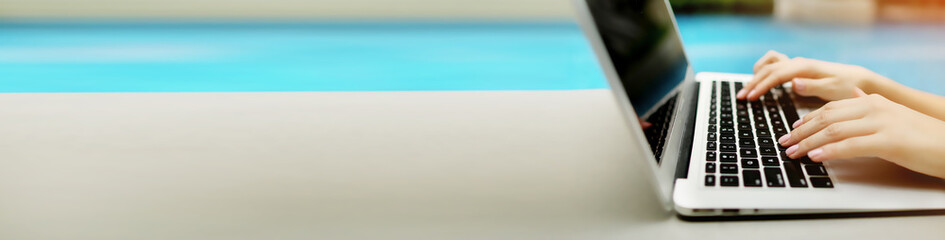 banner with copyspace in grey color of laptop and female hands, blue background. concept of website 