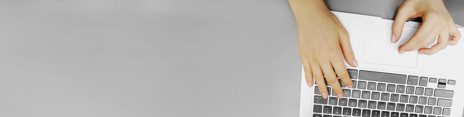 banner of top view laptop keyboard and female hands with copyspace in grey color background. concept