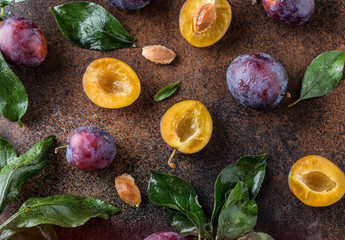 Wall Mural - Garden plums on table. Close up of fresh plums with leaves. Autumn harvest of plums.