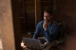 © Wavebreak Media - Man sitting on chair and using laptop in cabin porch