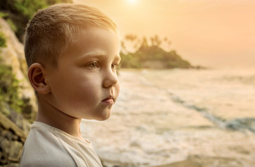 Child stay on the sea costline. Tropical beach under sunset sky