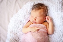 Cute Caucasian Newborn Infant Baby Girl Asleep Wrapped In A Soft Pink Plaid.  Adorable Newborn Baby Girl Portrait Studio Stock Image.