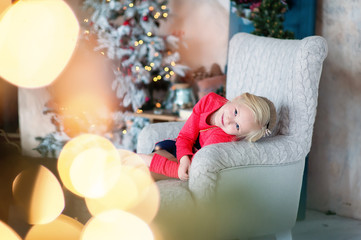 The beautiful smiling girl with a fair hair indoors with a Christmas interior