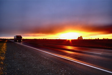 Picturesque landscape scene and sunset above road.