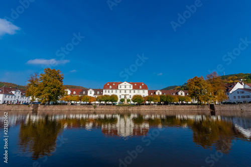 Fotomural Beautiful panoramic view of a row of baroque houses and the Huguenot Museum in the middle, mirrored on the water surface of the harbour basin on a nice autumn day in Bad Karlshafen, Germany